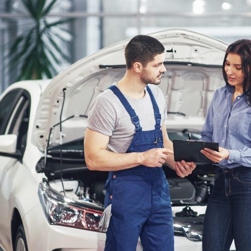 A man mechanic and woman customer discussing repairs done to her vehicle.